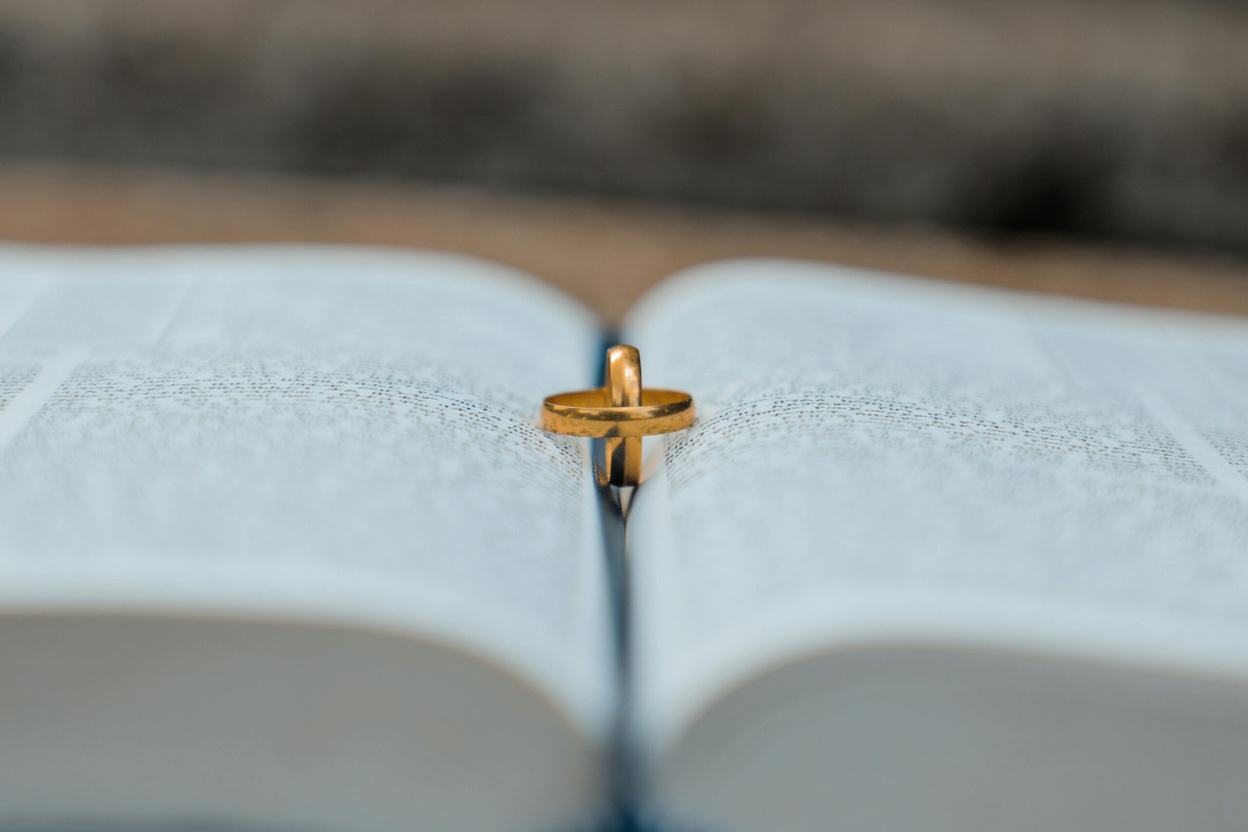 High angle of golden wedding rings placed on opened book during marriage registration