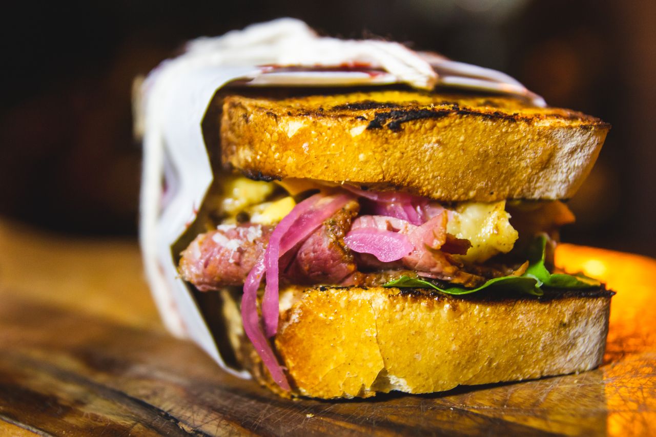 Close-up of a gourmet sandwich with beef, grilled bread, and fresh toppings. Perfect for lunch or dinner.